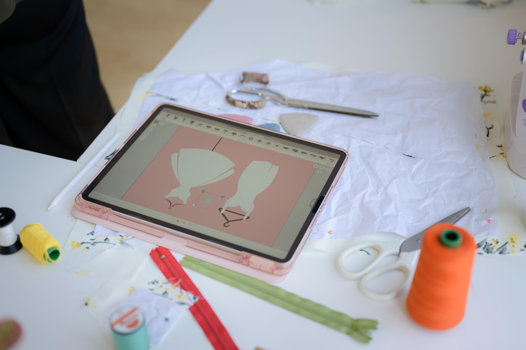Workshop desk with threads and modern tablet showing pattern